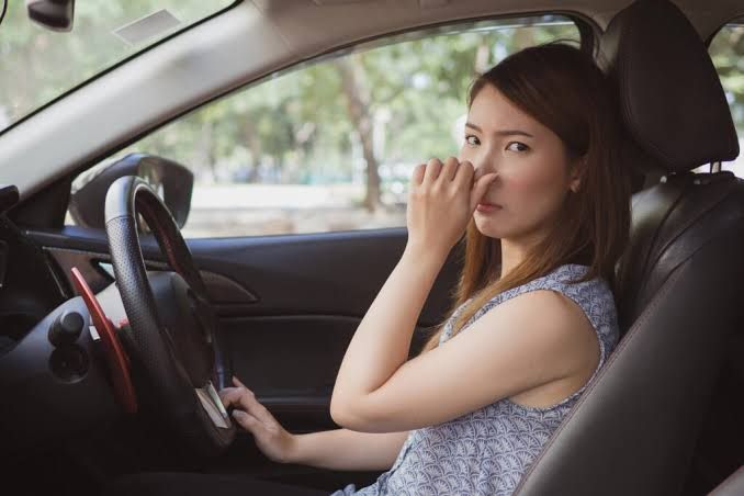 Driver pinching her nose because of a bad smell in the car